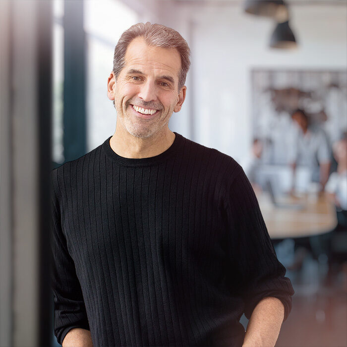 Doug Nathan standing with an office work space in the foreground, smiling